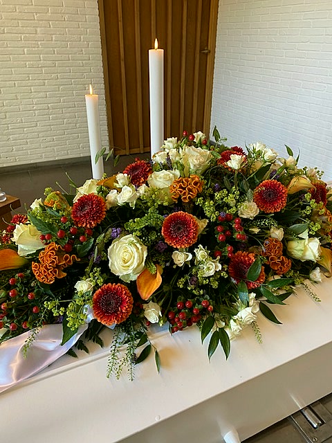 Kiste pyntet med blomster ved en bisættelse
